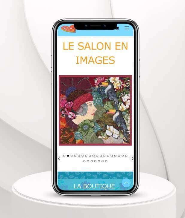 Smartphone affichant une oeuvre textile du salon BIAT, représentant une femme aux vêtements et chapeau bordeaux entourée d'oiseaux et de fleurs